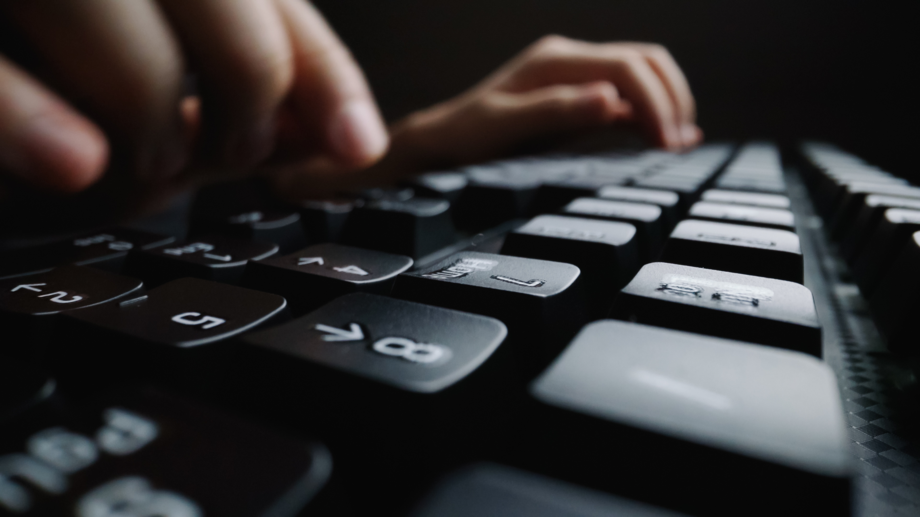 Soft-focus close-up of fingers typing on a computer keyboard